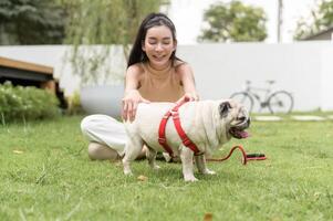 Happy asian woman playing with Cute Smart pug Puppy Dog In the Backyard photo