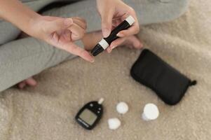 Close up of woman checking blood sugar level by using Digital Glucose meter, health care, medicine, diabetes, glycemia concept photo