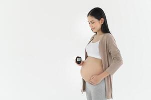 embarazada mujer comprobación sangre azúcar nivel por utilizando digital glucosa metro, salud cuidado, medicamento, diabetes, glicemia concepto foto