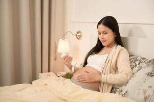 Beautiful pregnant woman applying moisturizing, stretch mark cream on belly, fertility infertility treatment, IVF, future maternity concept photo