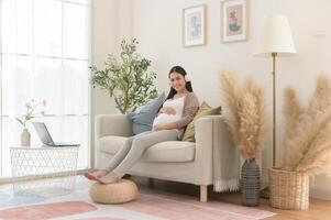 Happy pregnant woman with headphones listening to mozart music and lying on sofa, pregnancy concept photo