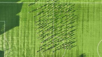 aéreo ver en parte superior fútbol equipo formación en un soleado campo, un grande grupo de joven fútbol jugadores tren en un soleado campo, demostrando trabajo en equipo video