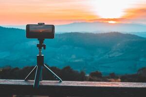 A smartphone is recording the sun setting over a mountain range. photo