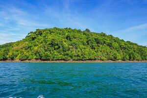 Aerial panorama of Thailand's verdant, lush tropical island, National Park Island, with blue and aquamarine the sea, and clouds shining by sunlight in the background. photo