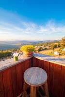 A view of the hill from the coffee shop, including a sunset in the background and a wooden chair placed into a corner. photo