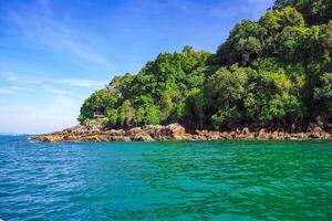 Aerial panorama of Thailand's verdant, lush tropical island, National Park Island, with blue and aquamarine the sea, and clouds shining by sunlight in the background. photo