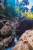 In the tropical forest of Kanchanaburi, Thailand's national park, waterfall flows pass the rock crevices in front of the cave. photo