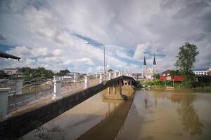 río ver con antiguo iglesia, el bautista torre terminado el ciudad horizonte y reflexivo aguas foto