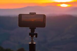 A smartphone is recording the sun setting over a mountain range. photo