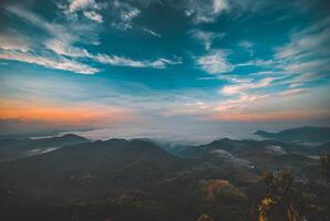 The stunning view from a tourist's standpoint as they go down a hill on a foggy trail with a hill and a background of a golden sky in Forest Park, Thailand. Rainforest. Bird's eye view. Aerial view. photo