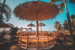 Beach chairs and umbrella on a tropical paradise island by the sea, under a sunny sky. photo