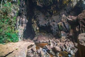 The beautiful views of the stalactite and stalagmite-filled cave in Lam Khlong Ngu National Park, Thailand. At the cave's exit is a small waterfall also. photo