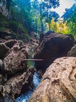 In the tropical forest of Kanchanaburi, Thailand's national park, waterfall flows pass the rock crevices in front of the cave. photo