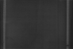 Black perforated metal round holes wall background with light leak. photo