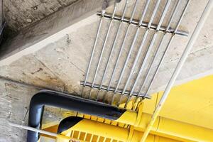 Electric metal pipe on raw and yellow concrete ceiling. photo