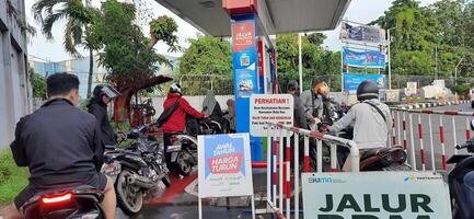 Long queue of motorbike drivers public refueling at Pertamina gas station. Bekasi, West Java, Indonesia - May 22 2024 photo