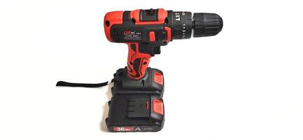 Electric red cordless screwdriver drill with charge the battery isolated on white background. Professional home repair tool. Bekasi, West Java, Indonesia - May 17 2024 photo