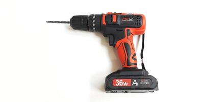 Electric red cordless screwdriver drill with charge the battery isolated on white background. Professional home repair tool. Bekasi, West Java, Indonesia - May 17 2024 photo