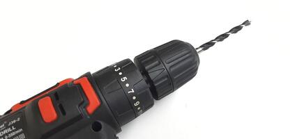 Electric red cordless screwdriver drill with charge the battery isolated on white background. Professional home repair tool. Bekasi, West Java, Indonesia - May 17 2024 photo