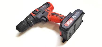 Electric red cordless screwdriver drill with charge the battery isolated on white background. Professional home repair tool. Bekasi, West Java, Indonesia - May 17 2024 photo