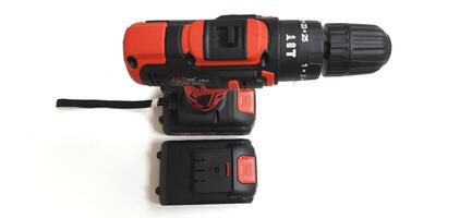 Electric red cordless screwdriver drill with charge the battery isolated on white background. Professional home repair tool. Bekasi, West Java, Indonesia - May 17 2024 photo