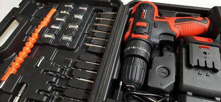 Electric red cordless screwdriver drill with charge the battery isolated on white background. Professional home repair tool. Bekasi, West Java, Indonesia - May 17 2024 photo
