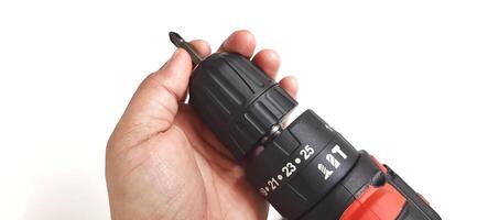 Electric red cordless screwdriver drill with charge the battery isolated on white background. Professional home repair tool. Bekasi, West Java, Indonesia - May 17 2024 photo