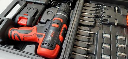 Electric red cordless screwdriver drill with charge the battery isolated on white background. Professional home repair tool. Bekasi, West Java, Indonesia - May 17 2024 photo