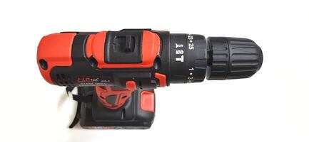 Electric red cordless screwdriver drill with charge the battery isolated on white background. Professional home repair tool. Bekasi, West Java, Indonesia - May 17 2024 photo