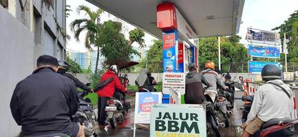 Long queue of motorbike drivers public refueling at Pertamina gas station. Bekasi, West Java, Indonesia - May 22 2024 photo