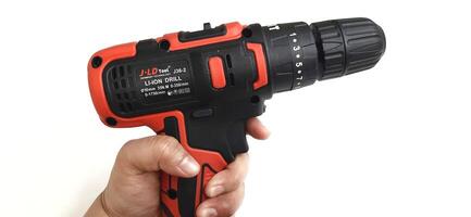 Electric red cordless screwdriver drill with charge the battery isolated on white background. Professional home repair tool. Bekasi, West Java, Indonesia - May 17 2024 photo