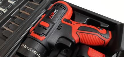 Electric red cordless screwdriver drill with charge the battery isolated on white background. Professional home repair tool. Bekasi, West Java, Indonesia - May 17 2024 photo