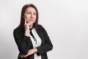Portrait thoughtful middle adult businesswoman wearing formal dress touching chin, standing on white photo