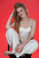 Portrait of young woman sincerely smiling, sitting on bar stool with feet up on it and looking away photo