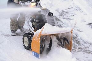 A male worker is using a snowblower to clear snow after a winter storm photo