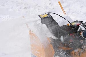 The snow blower effectively removes snow from the driveway in extreme close-up view photo