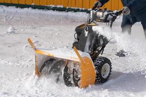 Worker using snow blower to remove snow after winter storm, assisted by snow thrower on winter road photo