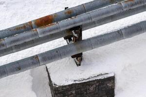 External city central heating pipes, with rusty thermal insulation jackets above snow after snowfall photo