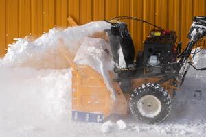 A man is using snow blower to clear snow after winter storm, with assistance of snowblower on road photo