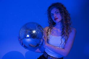Woman looks absolutely stunning as she poses with disco ball in nightclub. Blue party neon lights photo