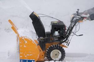 Snow blower machine in action. It's working hard to remove all snow from driveway in closeup view photo