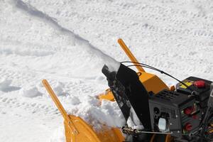 extremo de cerca ver de motor nieve soplador máquina lanzamiento fuera corriente de nieve mientras limpieza estacionamiento zona después nieve ciclón. motorizado quitando nieve foto