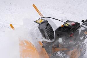 The snow blower effectively removes snow from the driveway in extreme close-up view photo