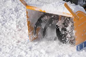 Snow blower machine mechanism is shown in extreme close-up throwing snow off road after blizzard photo
