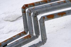 Pipes visible in winter, protruding above snow after snowfall. External city central heating pipes photo