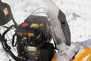 Extreme close-up of use of snow blower to remove snow after winter snow storm, assisted by snow thrower on road photo