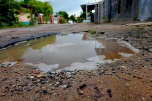 The dirt road has holes and puddles of rainwater full of mud with natural texture photo