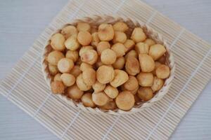Crispy fried macadamia nuts in basket on wooden table photo