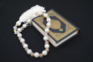 Holy Quran and rosary on black background, Ramadan Kareem photo