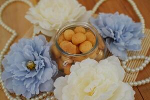 pastry in a glass jar and flowers on a wooden background photo